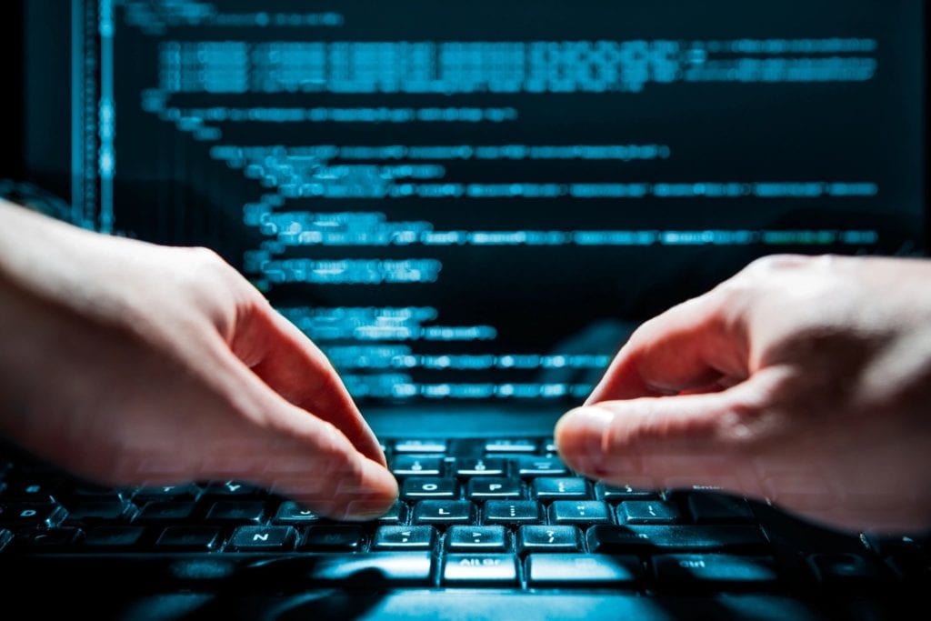 94129 A person typing on a keyboard with a computer screen in the background.